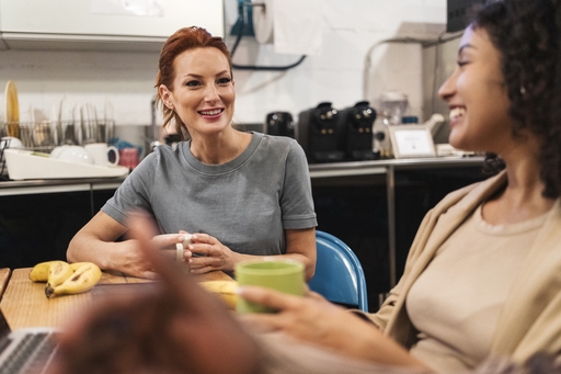 Two women sharing tea in a office kitchen