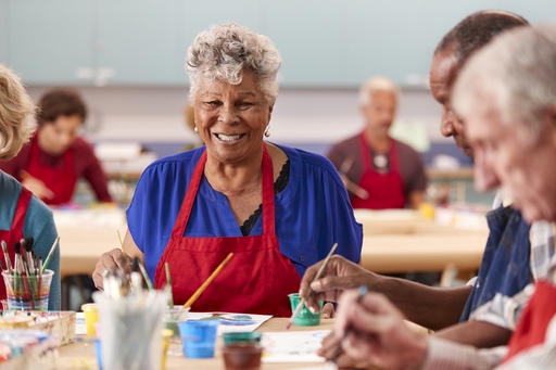 An elderly woman enjoying a group painting class.