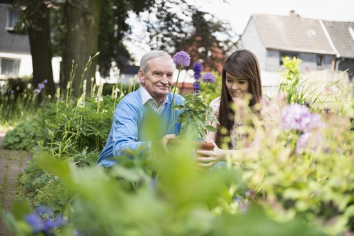 An elderly mand and a live-in carer enjoying being outside in a garden.