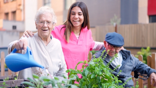An elderly couple watering plants with a live-in carer.