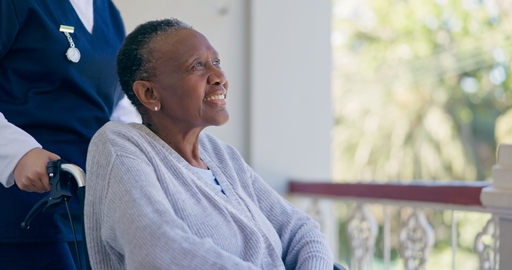 A lady sitting in a wheelchair receiving assistance from a live-in nurse.