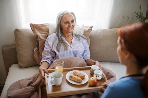 an elderly lady being served breakfast by a carer