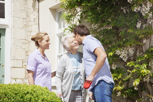 A live-in nurse with a patient outside being greeted by a relative.