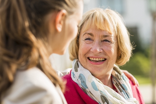 An elederly ladt smiling about something with her live-in carer.